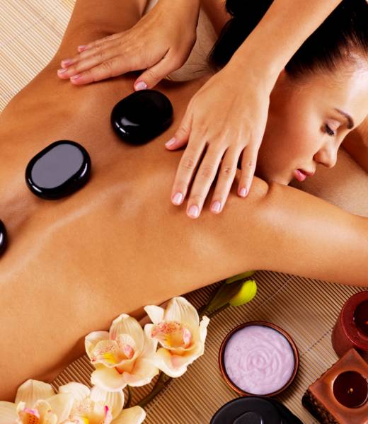 Adult woman having hot stone massage in spa salon. Beauty treatment concept.